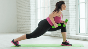 The girl performs an exercise with dumbbells